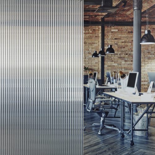 Modern open-plan office seen through fluted privacy film applied to a reeded glass partition.