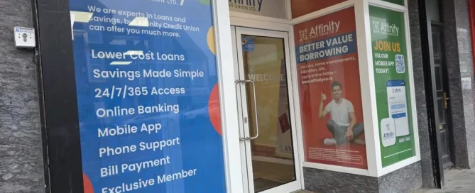 Affinity Credit Union shopfront displaying blue and red window graphics advertising loans and mobile banking.