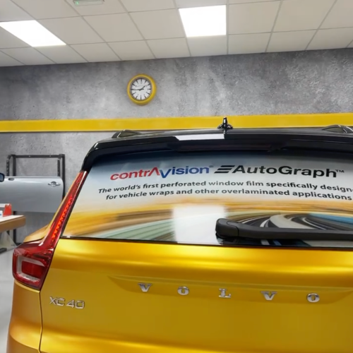 Rear window of a matte gold Volvo XC40 featuring Contra Vision AutoGraph perforated vehicle wrap film.