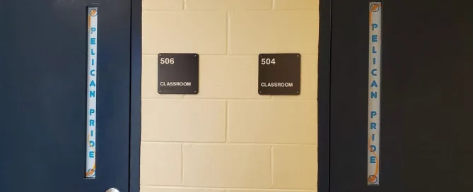 Two blue school classroom doors featuring custom Pelican Pride printed privacy window film on vertical glass panels.