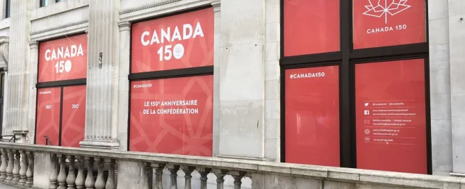 Canada House building windows covered in red anniversary window film with the text Canada 150 and maple leaf icons.