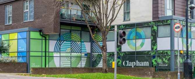 Exterior view of Clapham Park office building featuring green and blue branded Contra Vision window graphics.