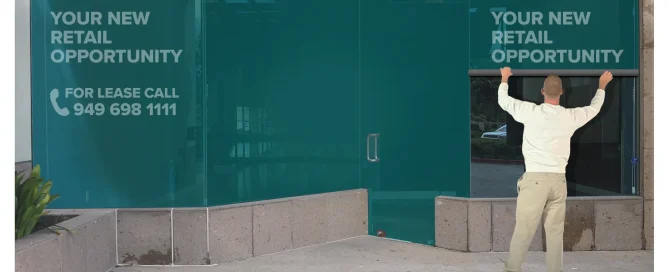A man installs teal Contra Vision retail window graphics reading Your New Retail Opportunity.