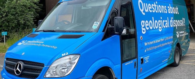 Bright blue Theddlethorpe GDF Community Partnership minibus featuring perforated window wrap for advertising.
