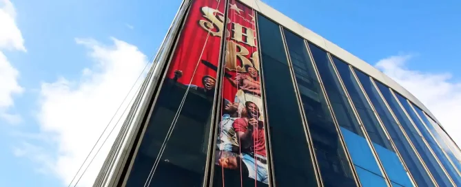 Large promotional theatre wrap on exterior glass windows at Gillian Lynne Theatre in London.