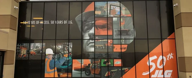 JLG building exterior featuring a large window graphic celebrating 50 years with machinery imagery.