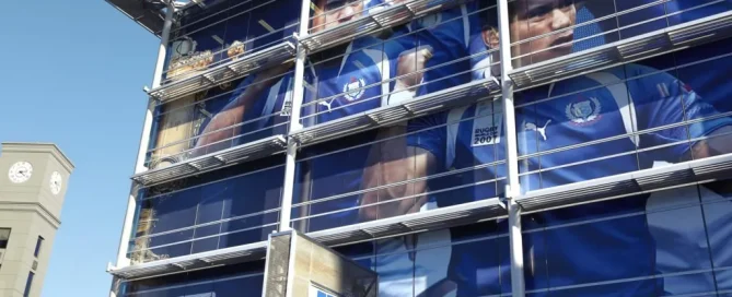 A large building glass facade wrapped in Rugby World Cup 2011 branding featuring players in blue uniforms.
