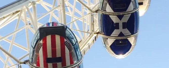 London Eye pods wrapped in colourful national flags using perforated window film against a clear blue sky.