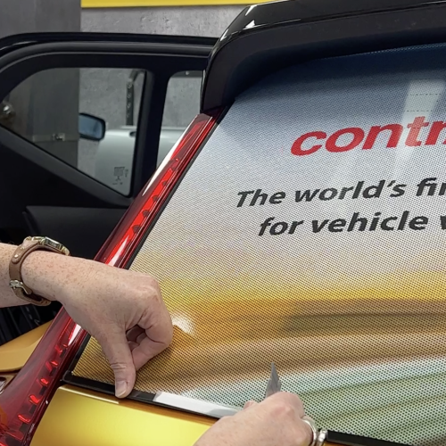 Hand applying clear gloss cast edge sealing tape to the rear window of a vehicle for graphics protection.
