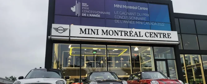 Mini MontrÃ©al Centre showroom front featuring promotional window graphics celebrating a dealer of the year award.