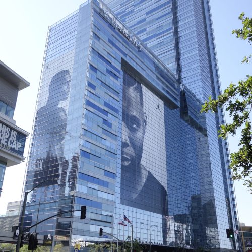 Massive Nike Jumpman perforated window film wrap on a glass skyscraper facade, showing a monochrome athlete portrait.