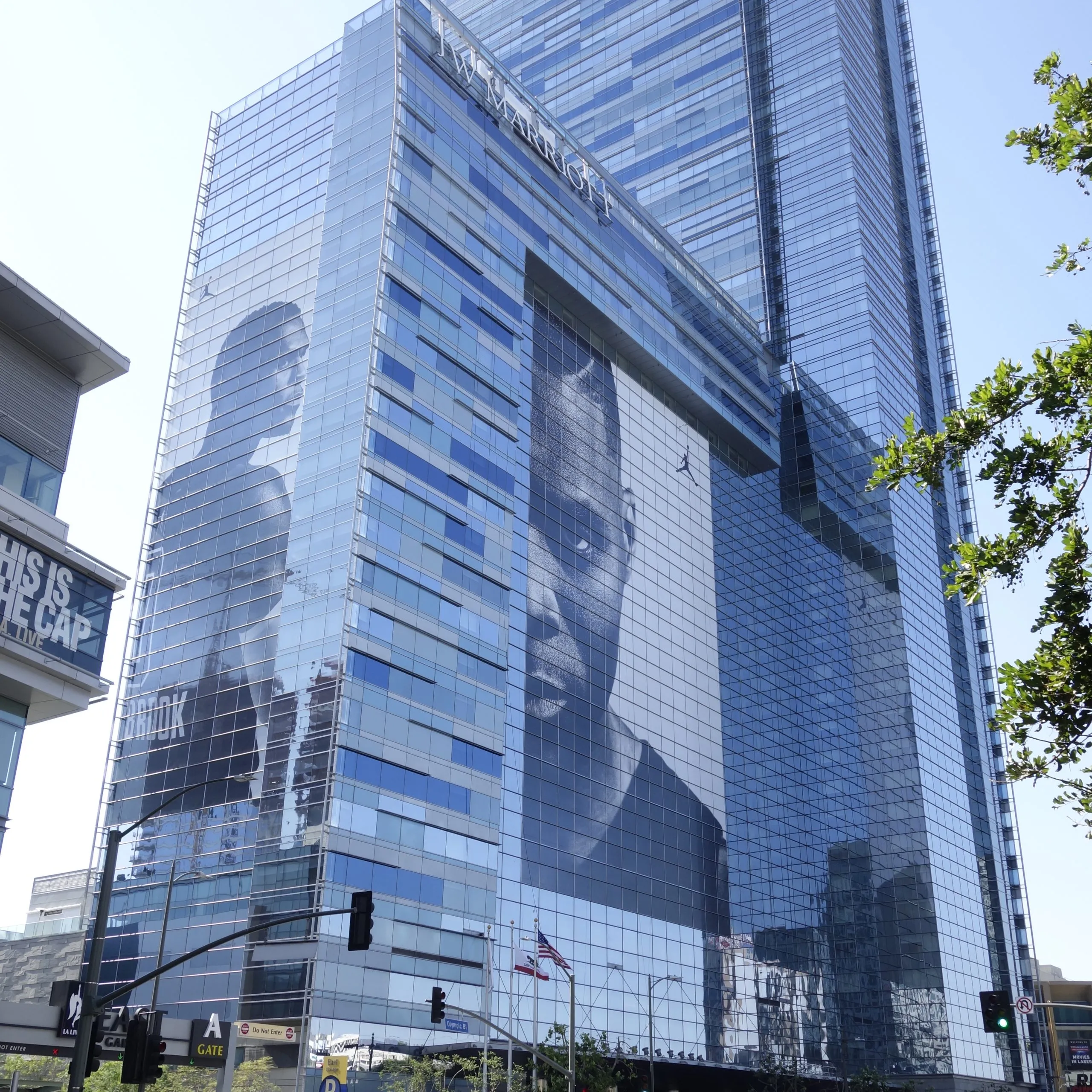 Massive Nike Jumpman perforated window film wrap on a glass skyscraper facade, showing a monochrome athlete portrait.