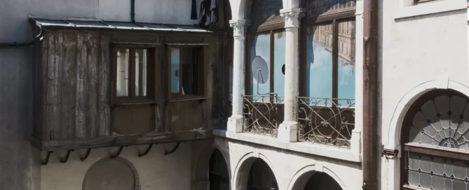 An architectural view of an old stone building in Venice with decorative art installation films on the windows.