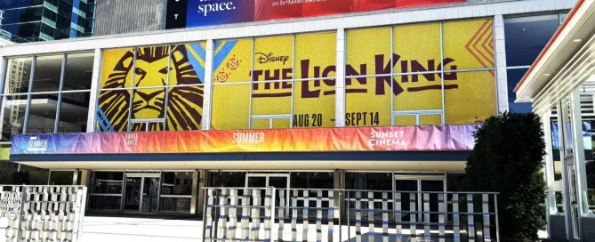 Exterior of Queen Elizabeth Theatre with large Lion King graphic printed on perforated window film.