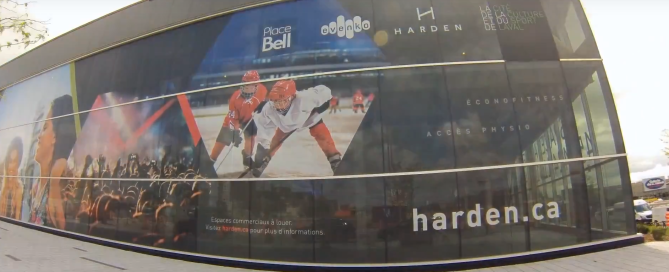 Place Bell exterior window graphics showing ice hockey players and a crowd, advertising retail leasing.