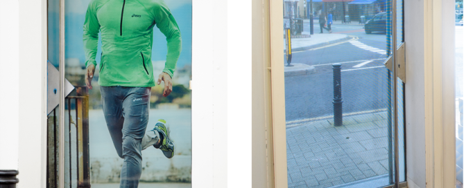 ASICS retail entrance featuring one-way vision graphics showing a male runner on the exterior glass.