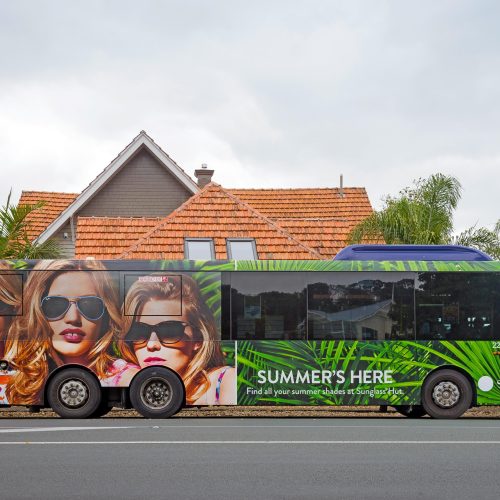 Sunglass Hut promotional bus wrap displaying a Summer's Here marketing graphic.