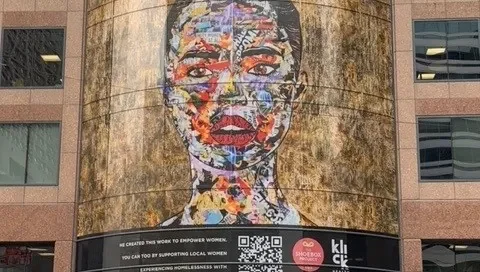 Large portrait artwork on a curved glass building facade for The Shoebox Project, applied with perforated window film.