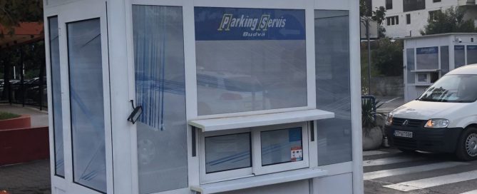 A white modular Parking Servis booth with glass windows located outdoors on a paved area.