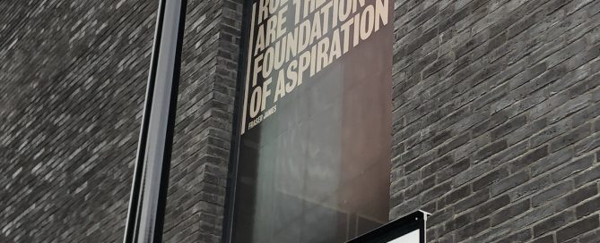 Brick building window displaying Role Models text graphics above a New Theatre Walk Southwark street sign.