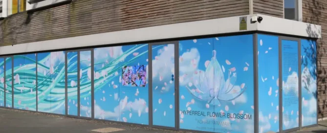 Large glass facade wrapped in blue floral art by Adham Faramawy using perforated window film.