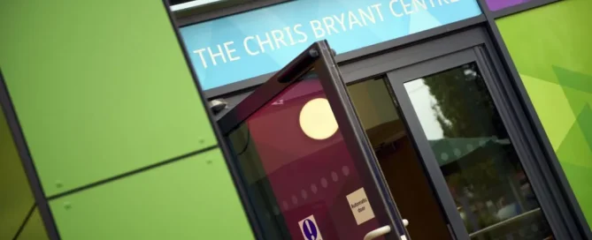Glass entrance door at The Chris Bryant Centre featuring colourful decorative window film graphics.