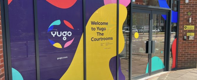 Yugo student accommodation entrance featuring colourful abstract window graphics and wayfinding signage.