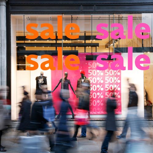 Retail storefront window with a sign advertising a fifty per cent off clothing sale.