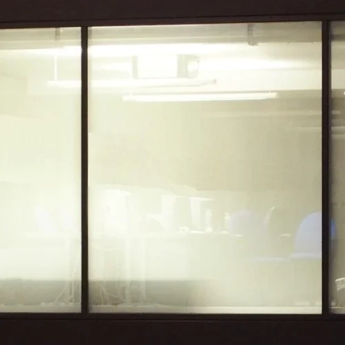 Close-up of a translucent micro-perforated window film obscuring the interior of an office space.